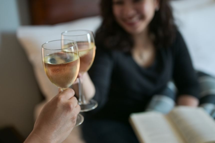 Close-up of a couple toasting wine glasses in a cozy room at Rodd Grand Yarmouth, a luxury hotel in Yarmouth