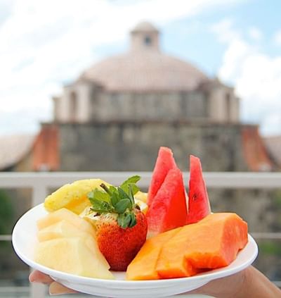 Plate of fruits with a blurred historic building in the background at Billini Hotel Historic Luxury
