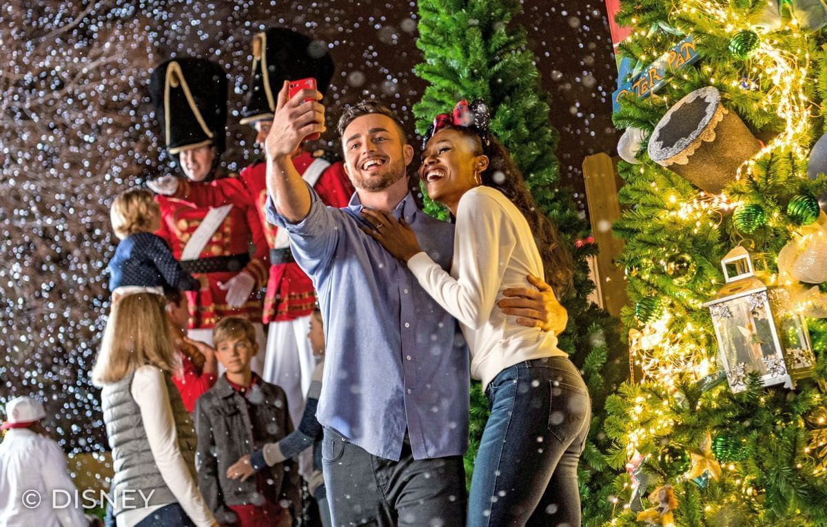Couple taking selfies by a Christmas tree and nutcracker decoration at Lake Buena Vista Resort Village & Spa