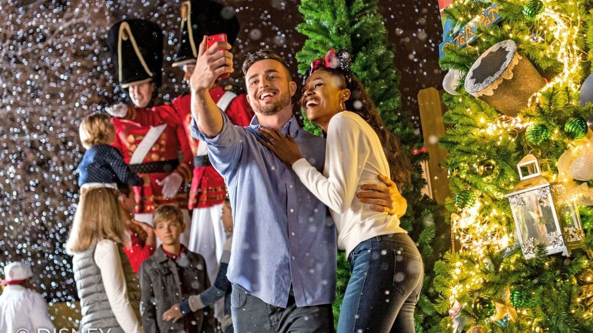 Couple taking selfies by a Christmas tree and nutcracker decoration at Lake Buena Vista Resort Village & Spa