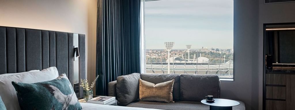 Deluxe Executive Room with king bed, sofa, and stadium views at Pullman East Melbourne.