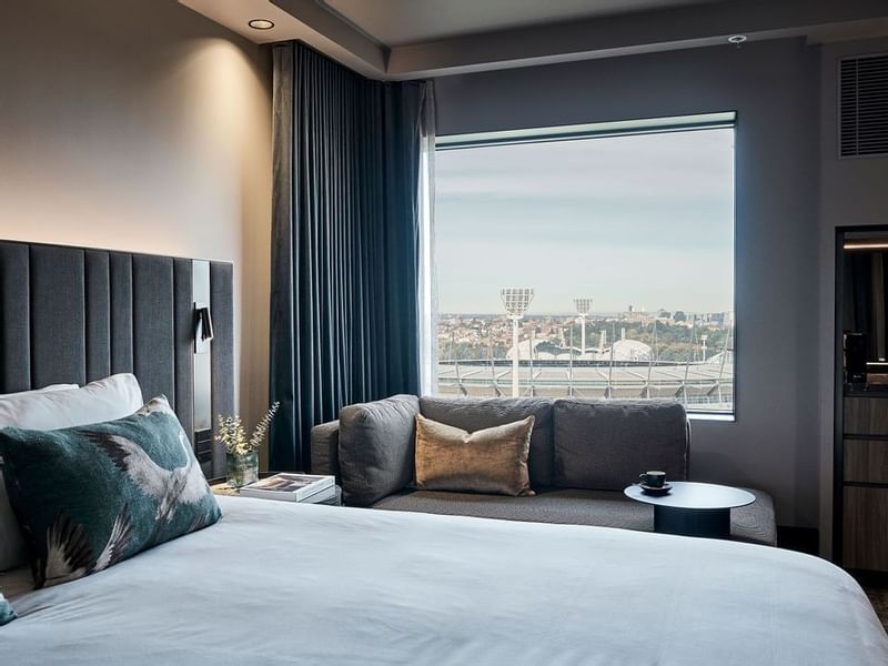 Deluxe Executive Room with king bed, sofa, and stadium views at Pullman East Melbourne.