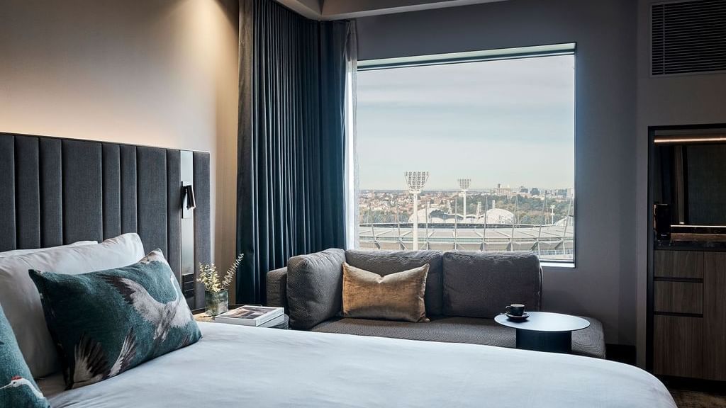 Deluxe Executive Room with king bed, sofa, and stadium views at Pullman East Melbourne.