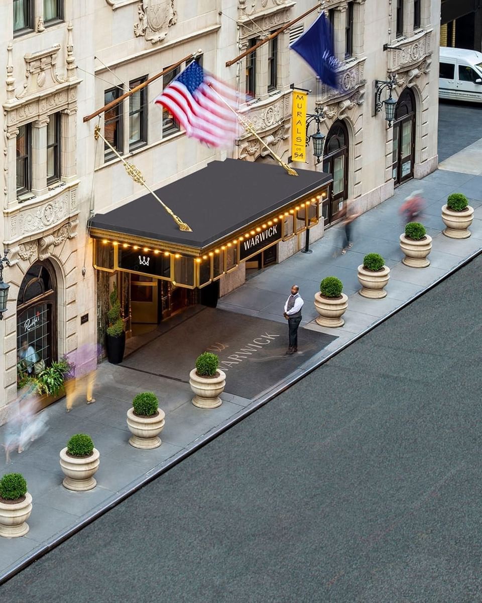 Exterior view of Warwick Corporate facade with national flags and potted plants lining the street entrance