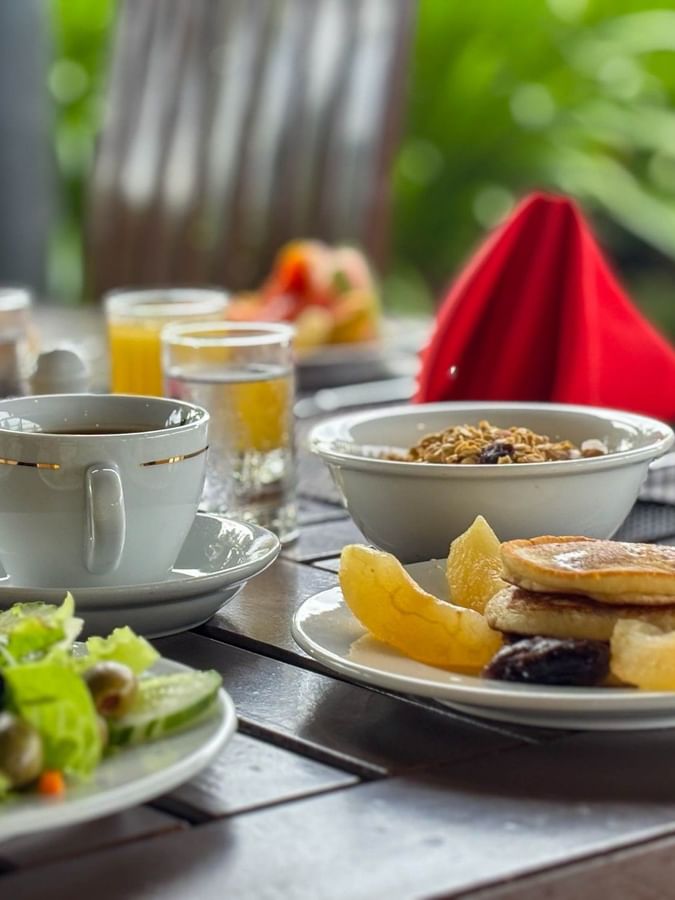 Plates of pancakes, salad, and fruit with coffee and orange juice at Nukunuku Restaurant & Bar in Korolevu