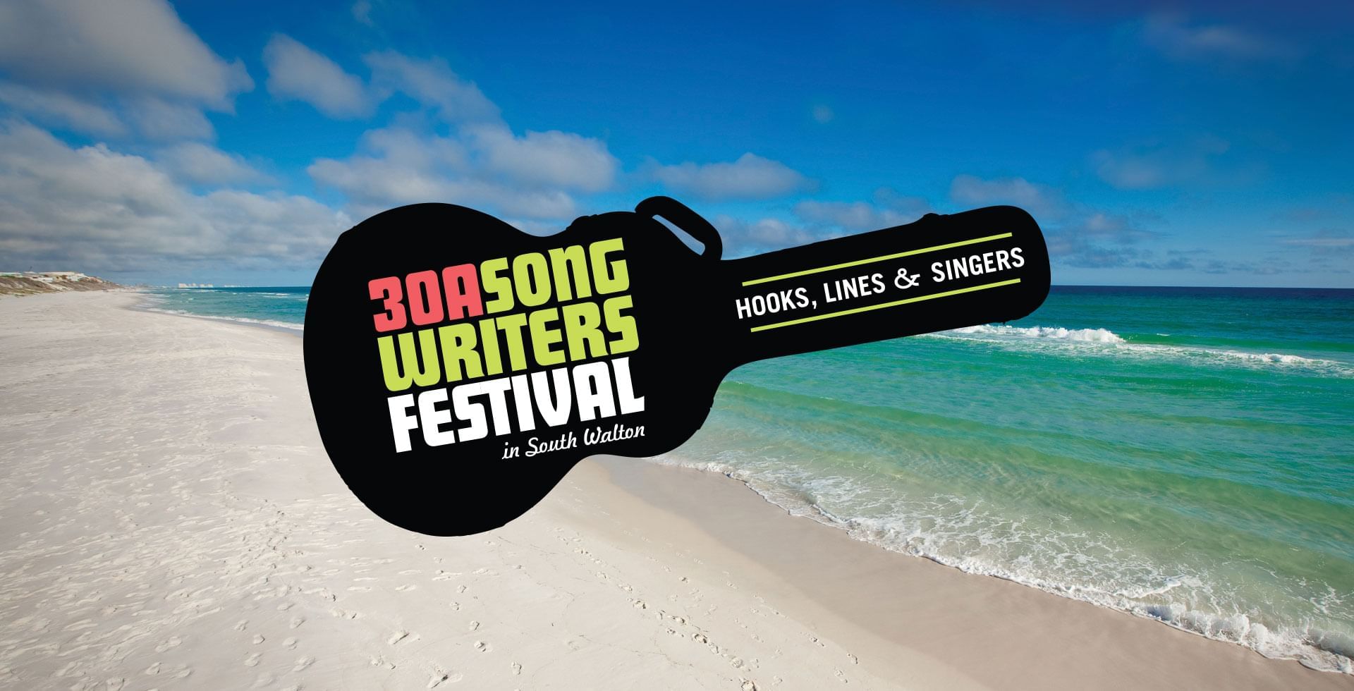 A guitar-shaped sign for the 30A Song Writers Festival hovers over a beach and ocean backdrop.