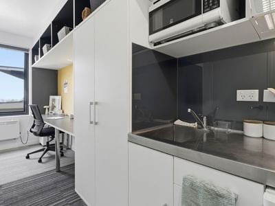 Modern kitchen with microwave, sink, and white cabinets at UniLodge Auckland City.