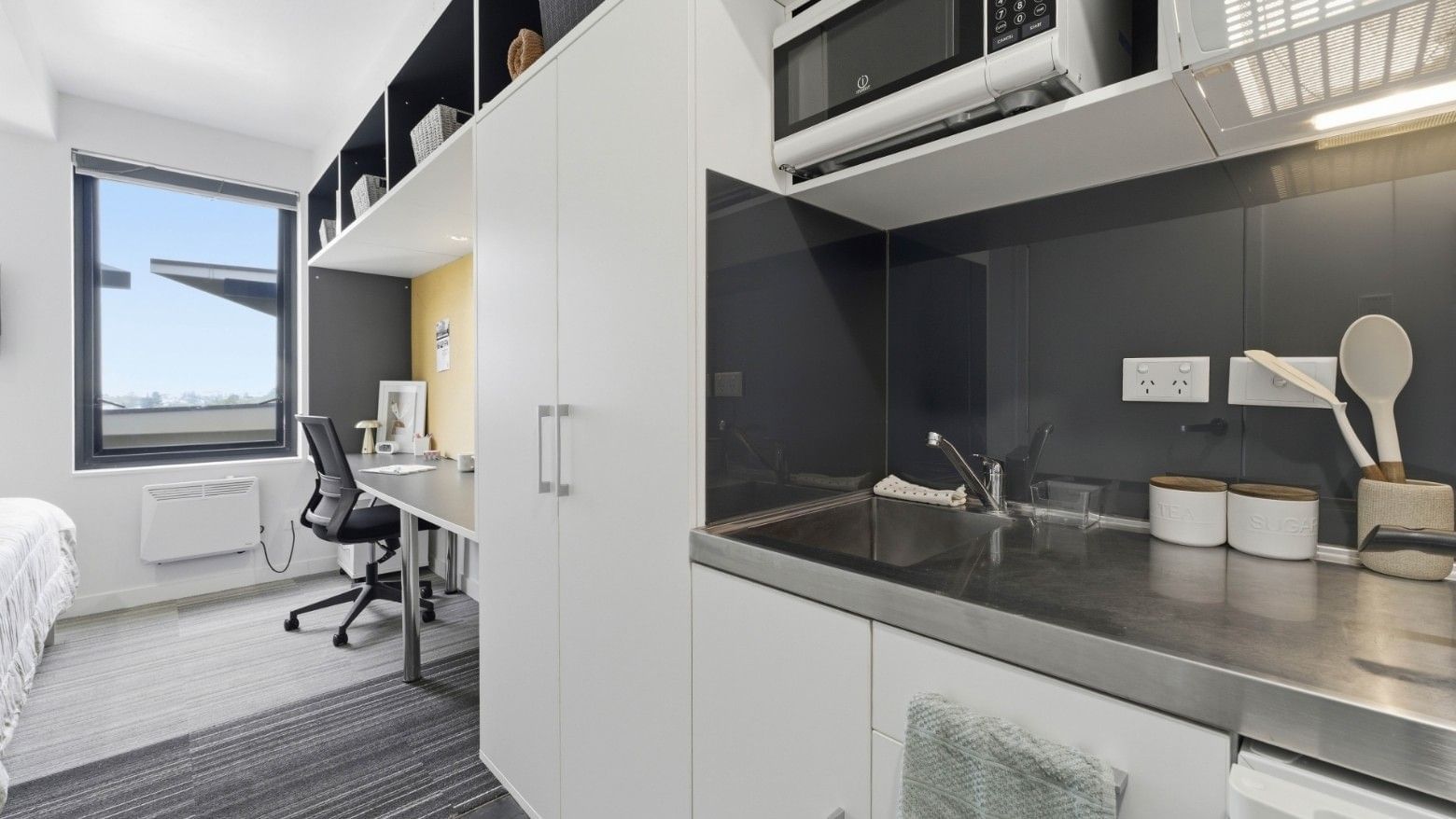Modern kitchen with microwave, sink, and white cabinets at UniLodge Auckland City.