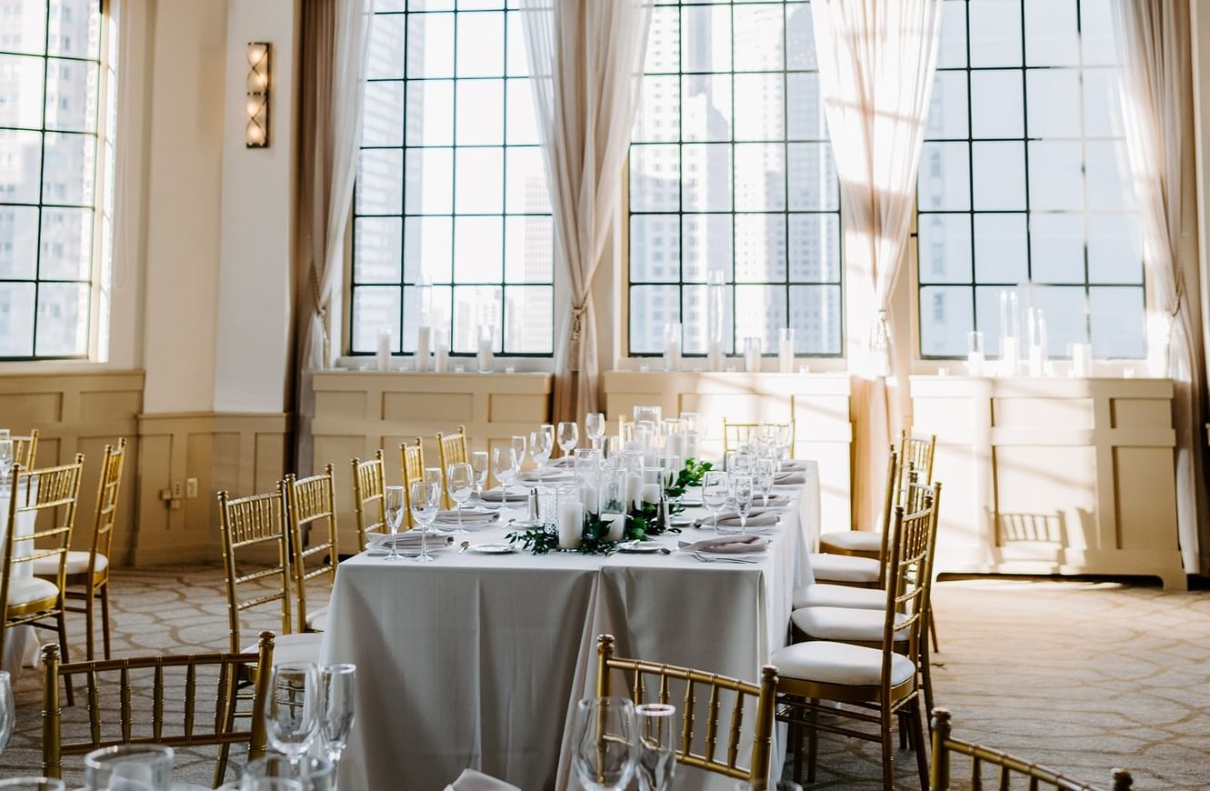 Elegant banquet room with long table setup under a chandelier by windows at Warwick Allerton Chicago