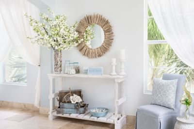 Bright entryway with a driftwood mirror, flower arrangement, and coastal decor in Drift Spa at Windsong Resort On The Reef