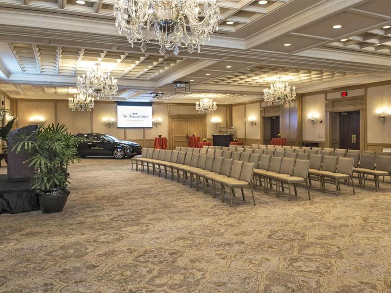 rows of chairs and a car in a ballroom