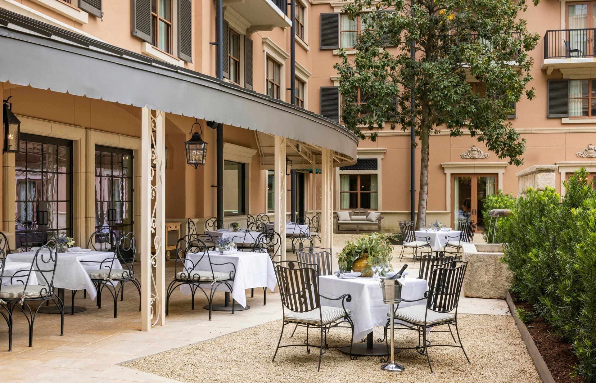 The Garden Courtyard at Granduca Houston with white tablecloths, chairs, and lush garden surroundings