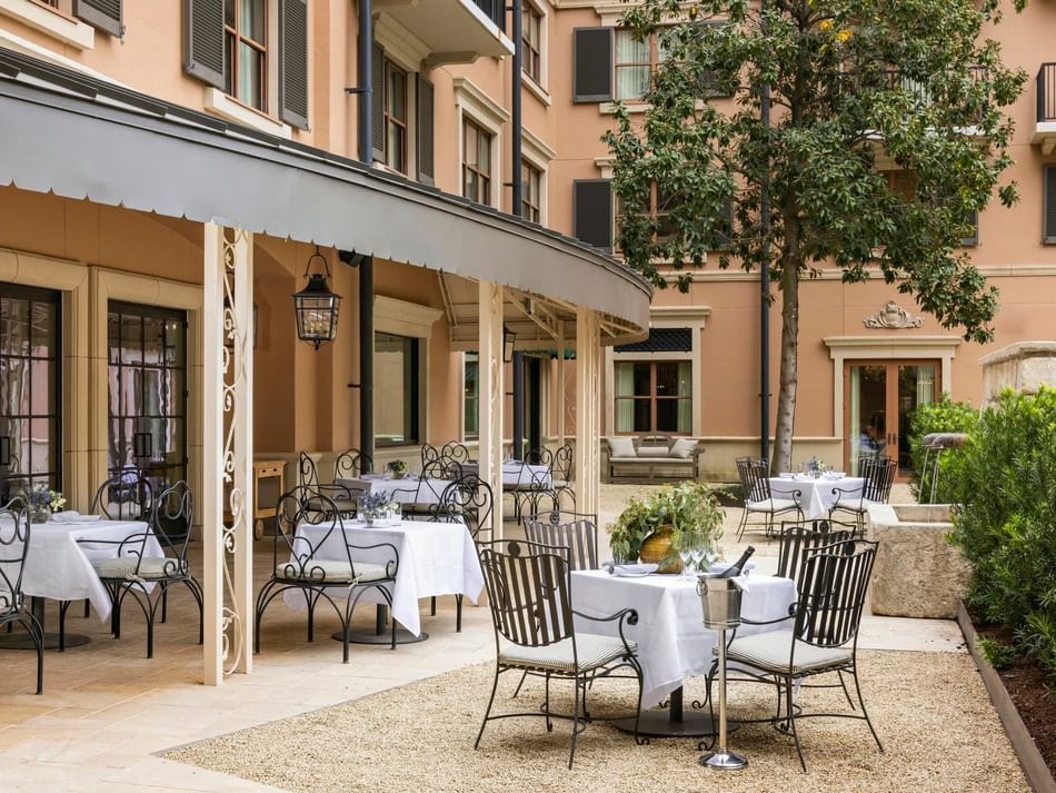 The Garden Courtyard at Granduca Houston with white tablecloths, chairs, and lush garden surroundings