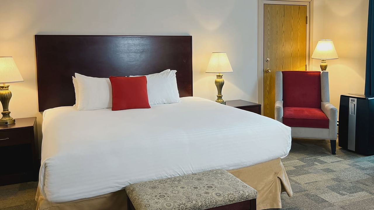 Premium King bedroom with bed, chair, air conditioning, lamp, and nightstands