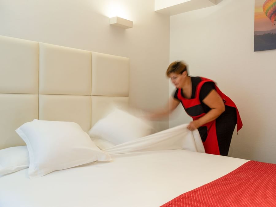 A lady arranging a bed in a room at Hotel Lecourbe