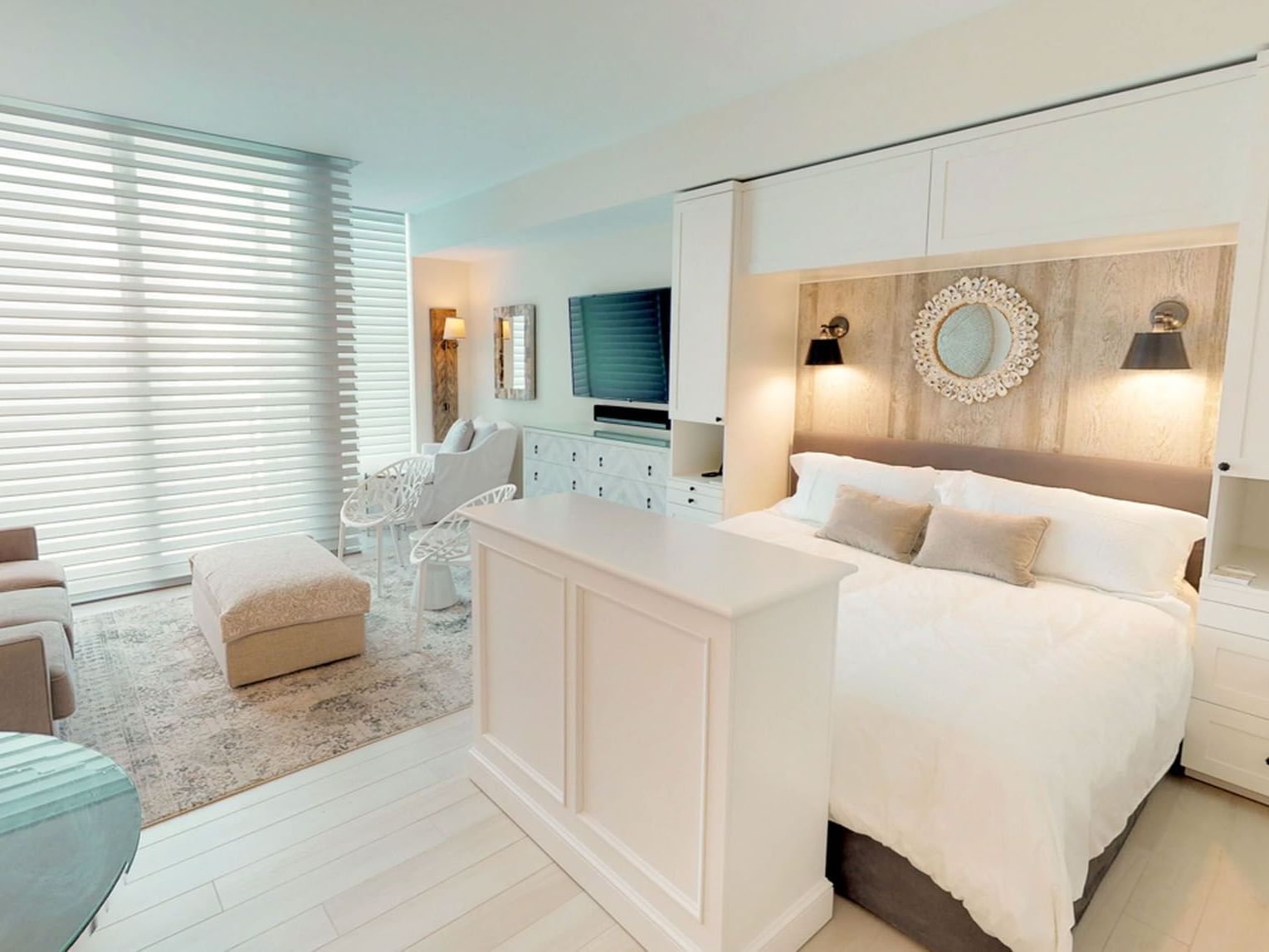 TV lounge area by the bed in N503 Room featuring stylish blinds for natural light at The Residences at Seafire.