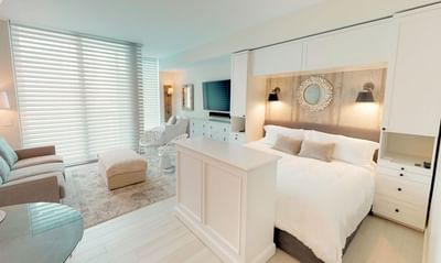 TV lounge area by the bed in N503 Room featuring stylish blinds for natural light at The Residences at Seafire