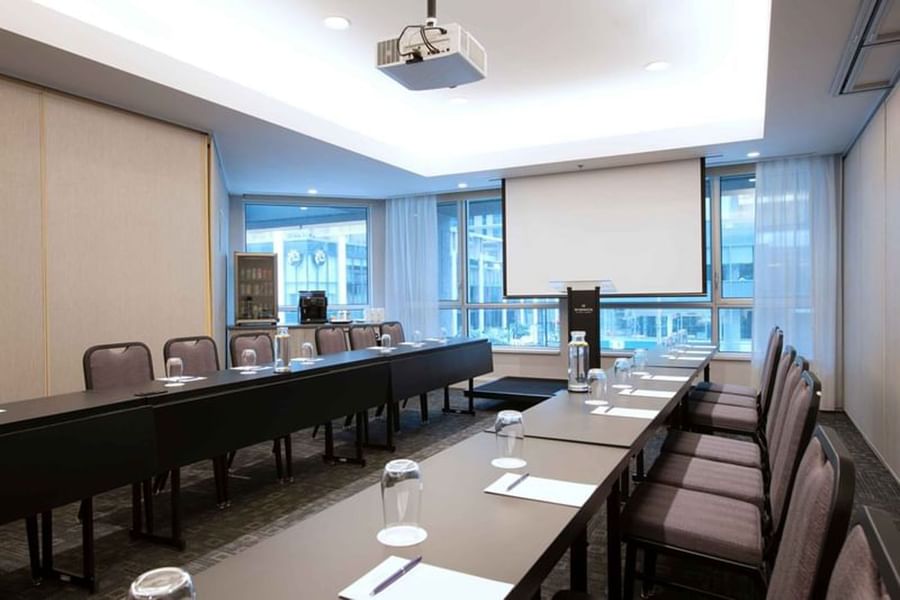 Long conference table with projector screen & city view at Warwick Le Crystal Montreal
