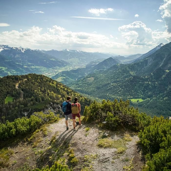 Two hikers with backpacks enjoying a mountain view near Falkensteiner Hotel Schladming
