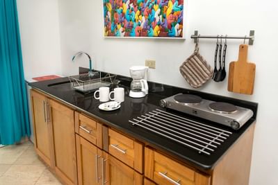 Kitchenette counter with a coffee maker and mugs by a hot plate in Junior Executive Suite at Hotel Montana Haiti