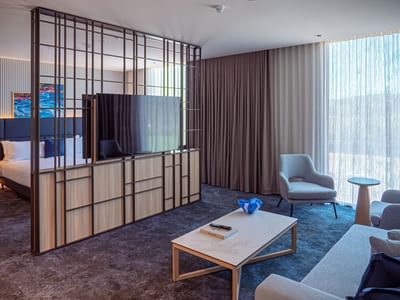 Bravo Suite featuring a partitioned TV lounge with plush seating and bed by the large windows at Encore By Mingara