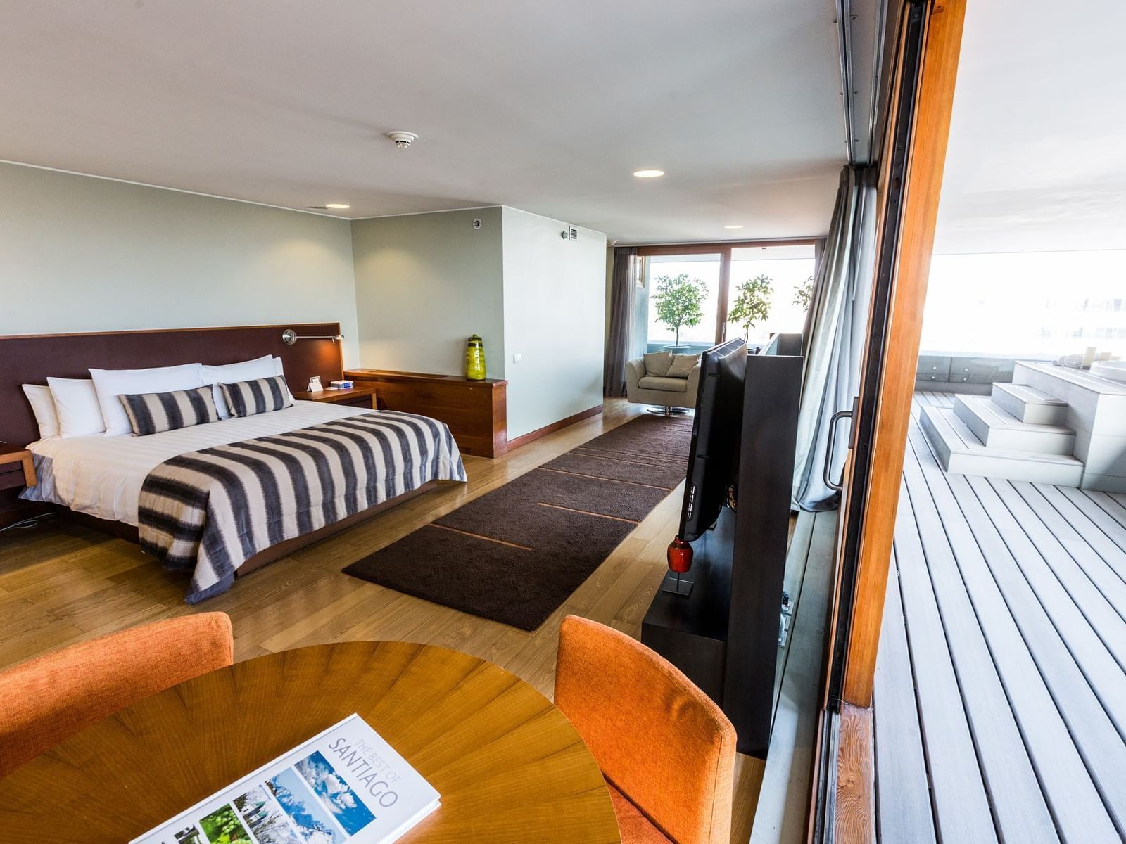 Cosmopolitan Suite espaçosa com cama king, piso de madeira, área de estar e terraço privativo no NOI Vitacura em Vitacura