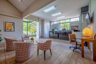 Lobby area with front desk, lounge chairs, coffee table & TV at Irazu Hotel
