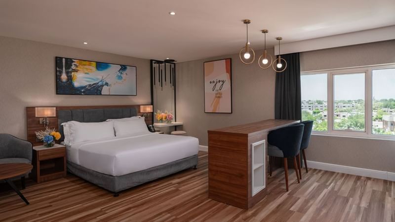 King bed by a tall wooden bar table and two chairs in Executive Room City View at Warwick Al Jubail