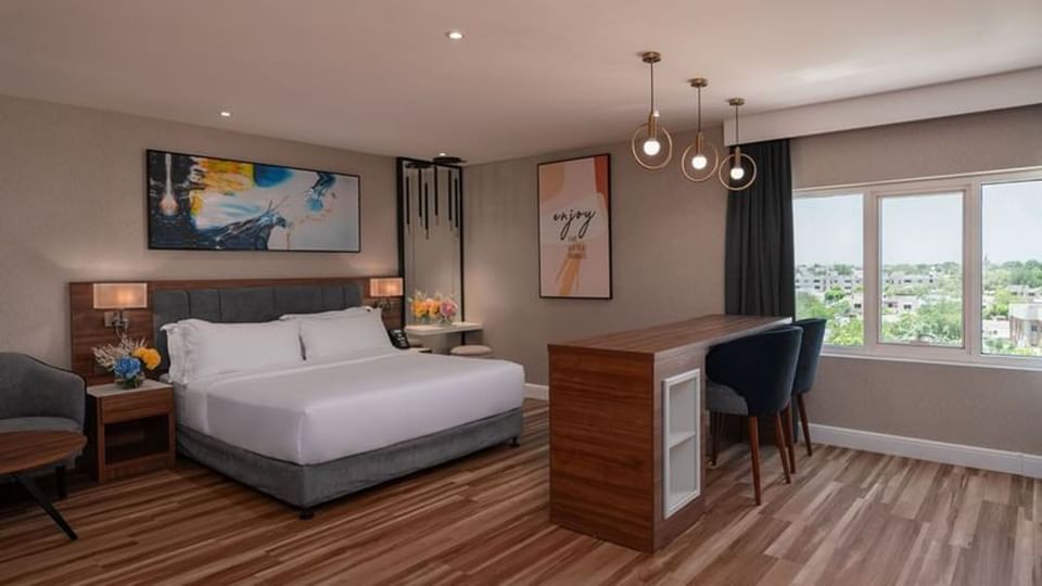 King bed by a tall wooden bar table and two chairs in Executive Room City View at Warwick Al Jubail
