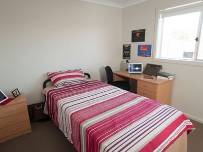 Clean room with bed, desk, chair, and window at La Trobe University Regional Housing – Shepparton.