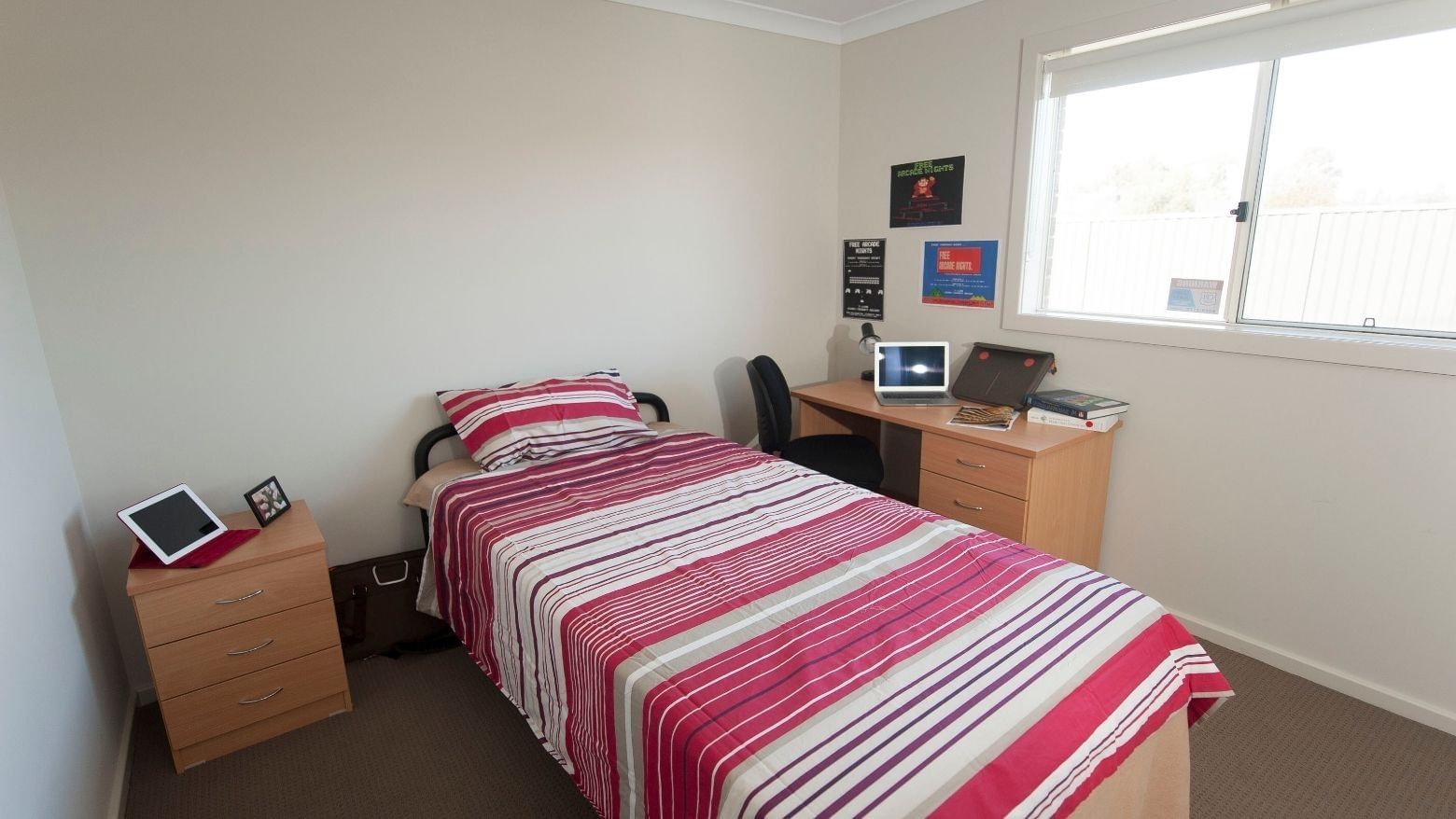Clean room with bed, desk, chair, and window at La Trobe University Regional Housing – Shepparton.