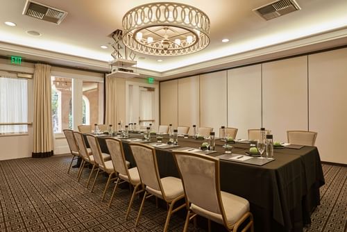 Boardroom set up under the stylish chandelier and carpeted floors at El Prado Hotel