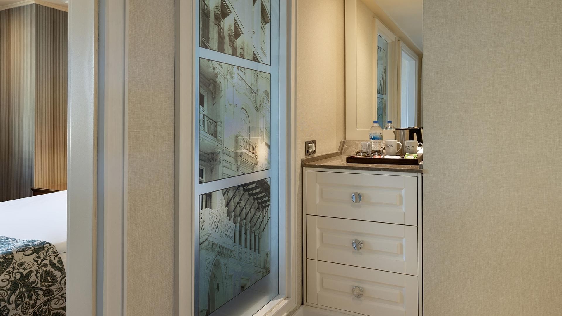 Titanic City Taksim'deki deluxe odaya açılan banyo kapısından görünüm, içeride çekmeceli dolap ve ayna var.
