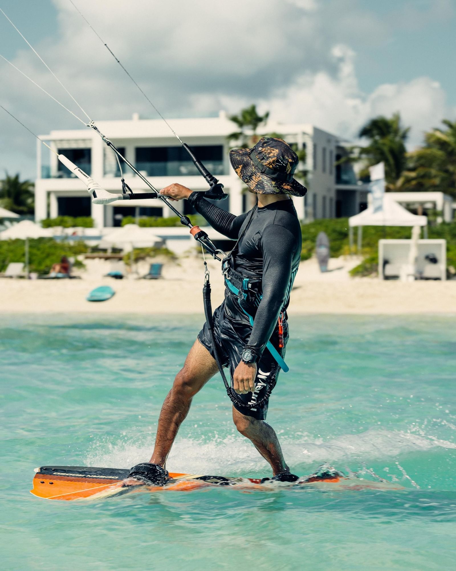 A kiteboarder riding the shallow turquoise water in front of H2O life.style.resort. on Long Bay Beach, Providenciales