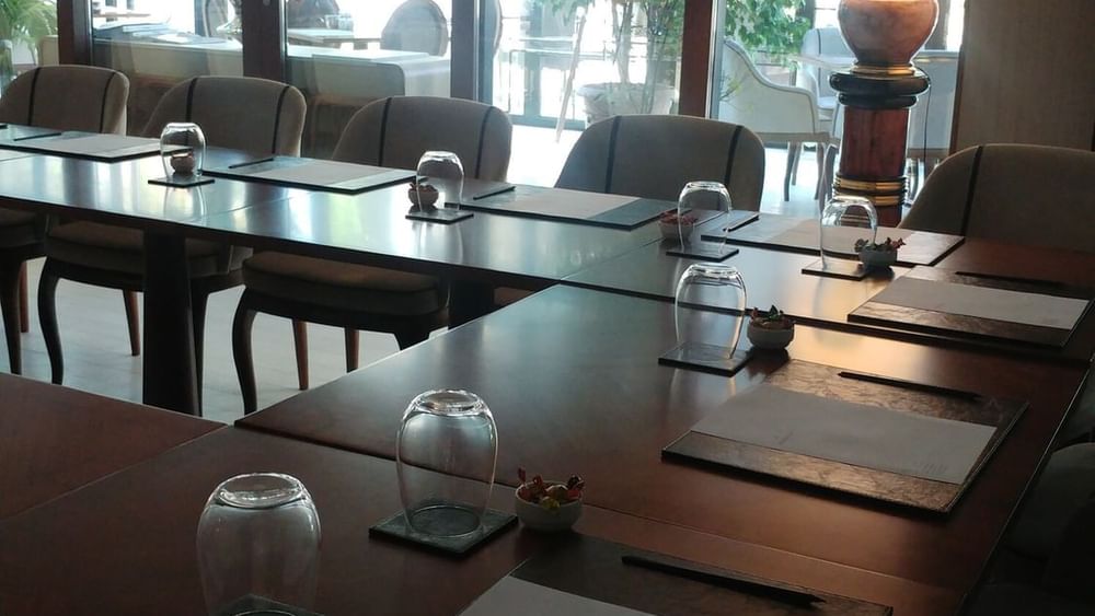 Kugu 2 Hall features Water glasses by paper pads surrounding a wooden table at Warwick Ankara