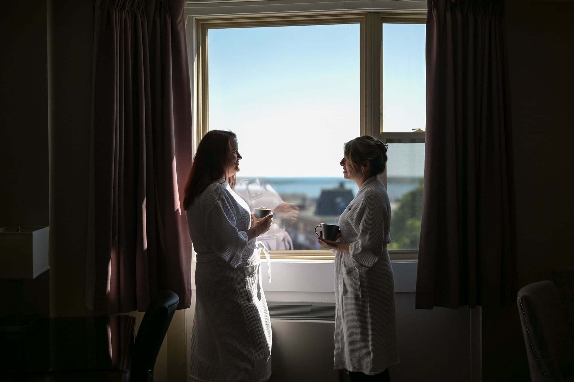 Couple enjoying a coffee by the window with scenic views at Rodd Grand Yarmouth, one of the best hotels in Yarmouth