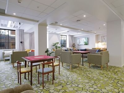 Modern communal lounge with game tables, seating areas, and natural light at UniLodge Auckland Central.