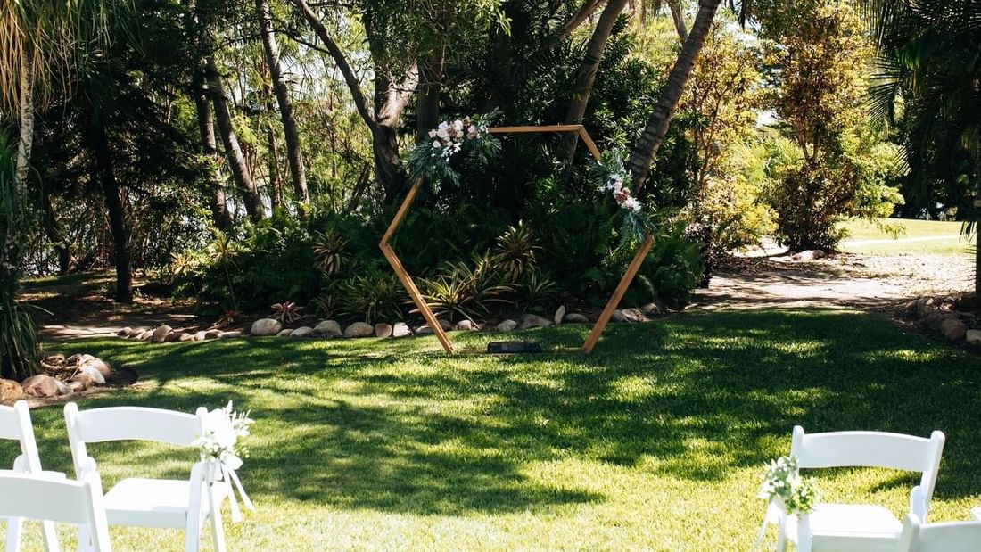 Outdoor wedding setup with a floral-adorned wooden arch at Mercure Hotel Townsville