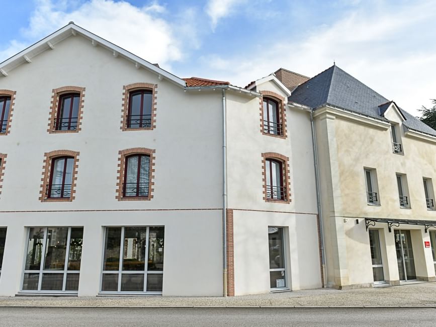 Façade moderne de l'Hôtel Rivella avec de nombreuses fenêtres et entrées vitrées.