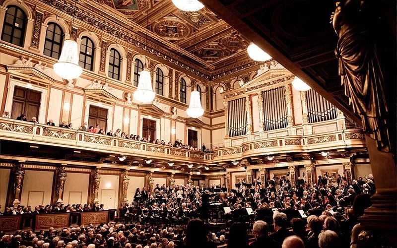 Prunkvoller Konzertsaal im Wiener Musikverein mit Orchester auf der Bühne und Publikum auf den Rängen.