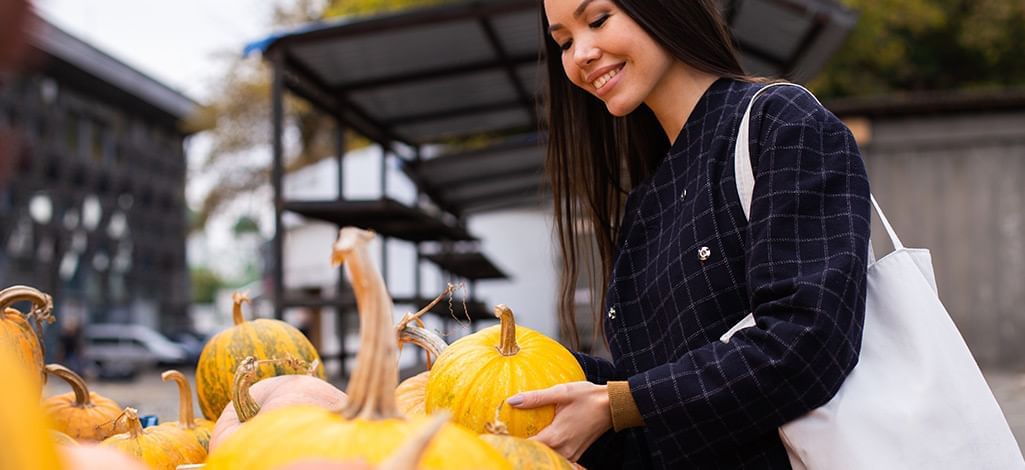 woman buying a pumpkin at a market