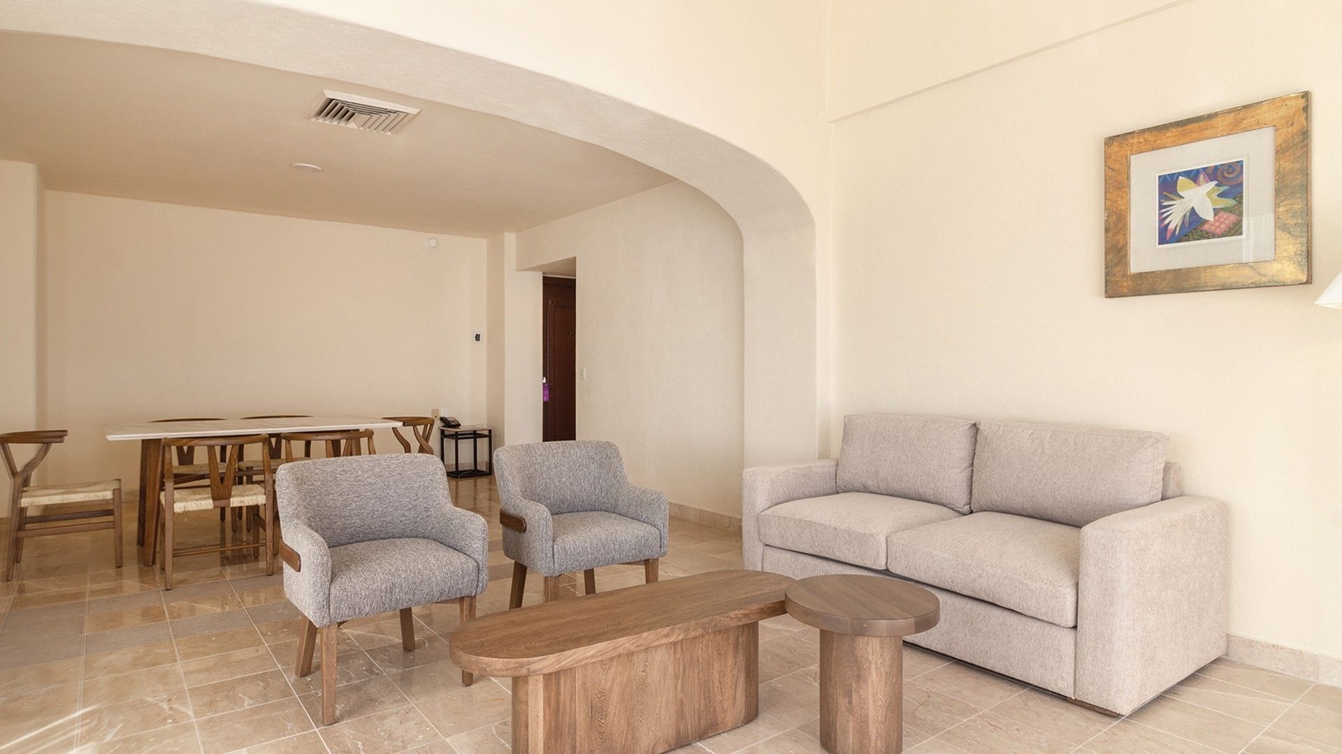 Living area with gray armchairs, a beige sofa, and wooden coffee tables in King Master Suite at Camino Real Acapulco Diamante
