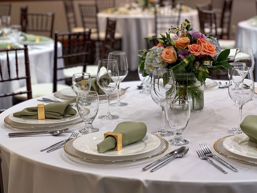Close-up of a table setting featuring green napkins by a floral centerpiece in Sasquatch Room A at Warwick Seattle