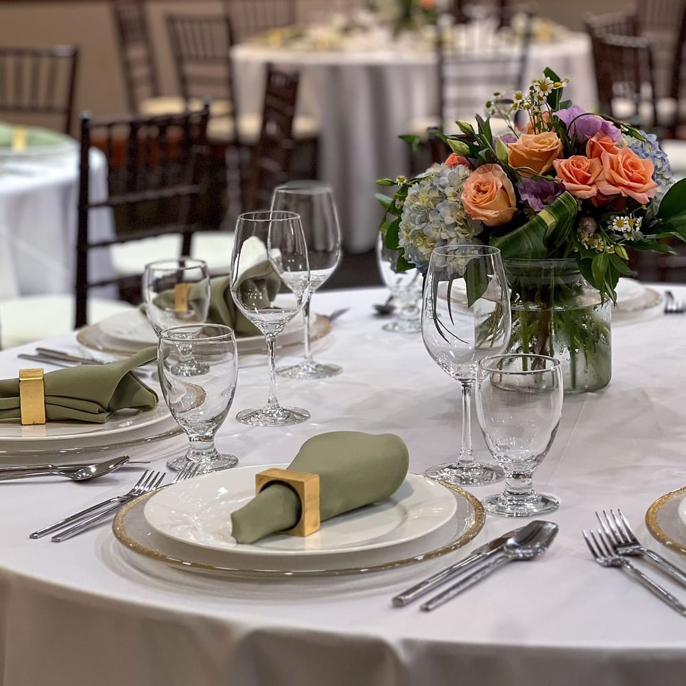 Close-up of a table setting featuring green napkins by a floral centerpiece in Sasquatch Room A at Warwick Seattle