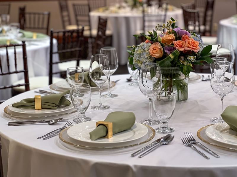 Close-up of a table setting featuring green napkins by a floral centerpiece in Sasquatch Room A at Warwick Seattle