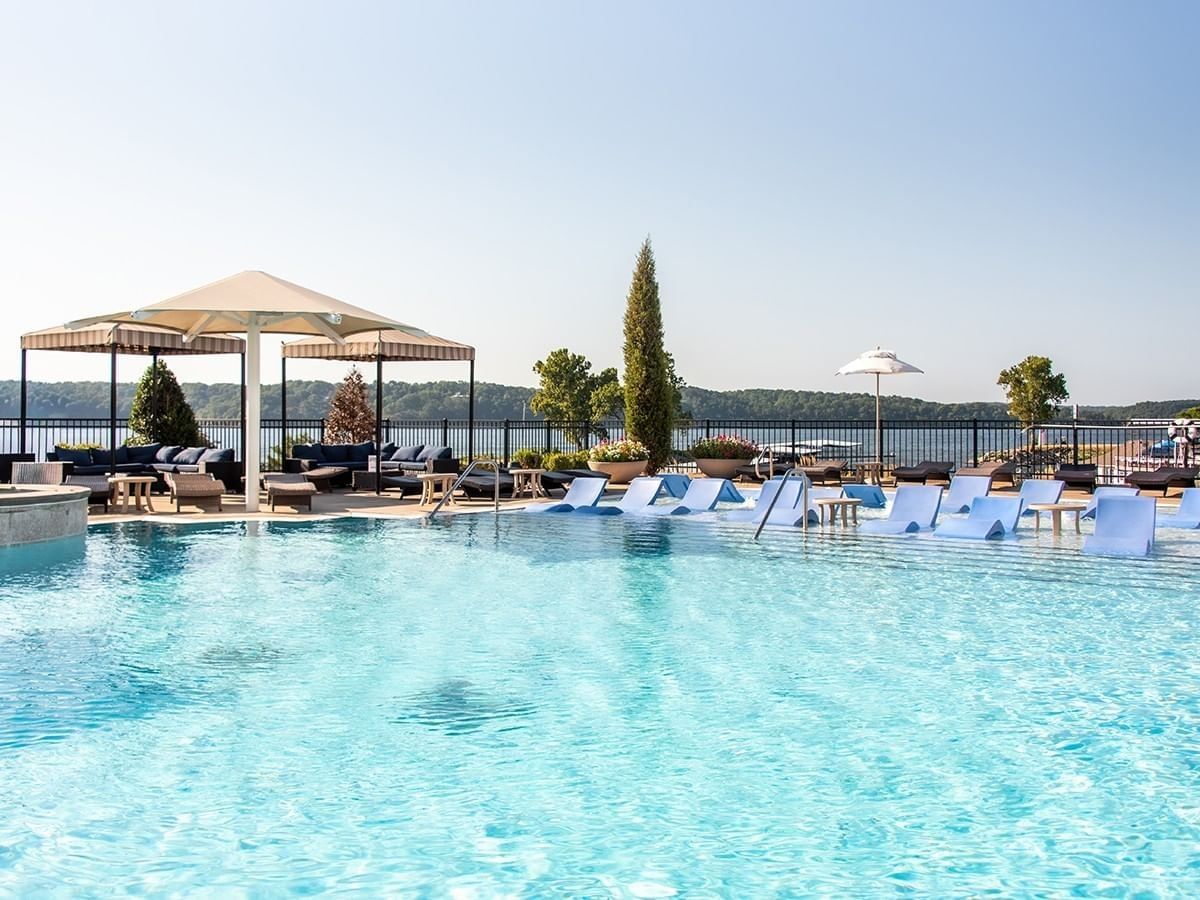 Luxury resort infinity pool with blue sun loungers and cabanas overlooking the lake at Shangri-La Resort and Golf Club