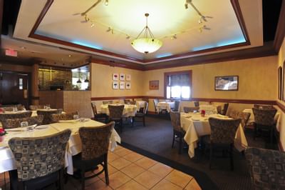 Elegant dining room with clothed tables and patterned chairs in Piccolo Arancio at Farmington Inn and Suites