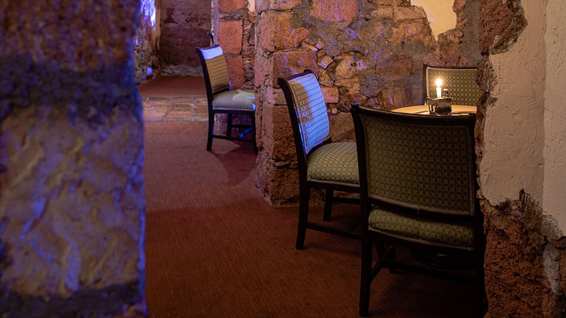 Cozy candlelit table in Bar Botarel tucked between historic stone walls for a private atmosphere at Quinta Real Zacatecas