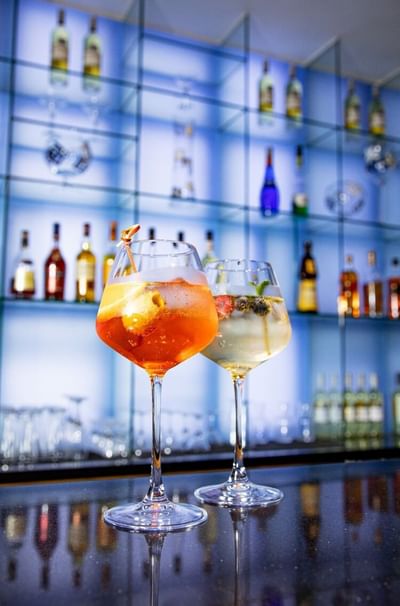 Two refreshing cocktails with colorful garnishes served at the elegant Marigold Bar in Park Hotel Hong Kong