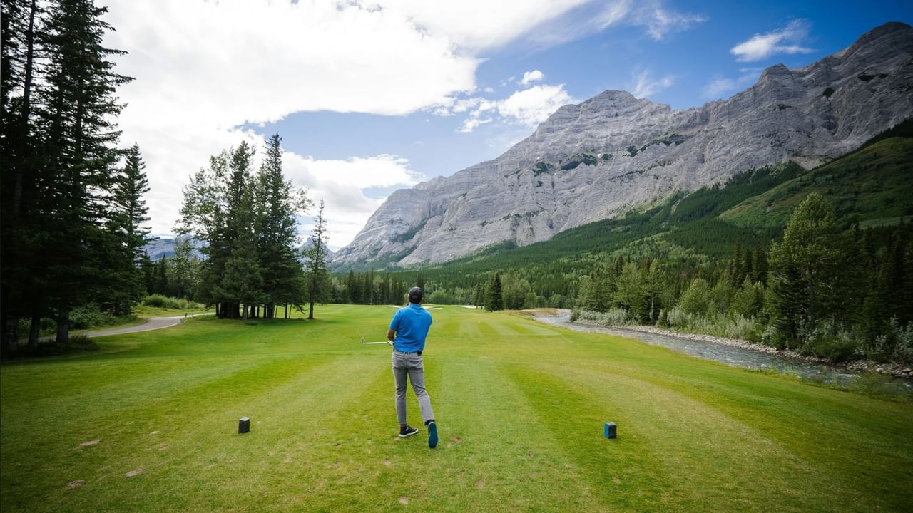 A person tees off on a Canmore golf course.